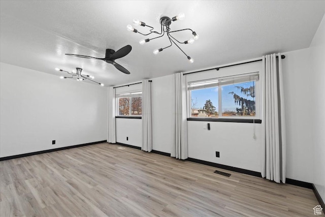 6357 W 3570 S, West Valley City, UT 84128 - spare room with baseboards, a notable chandelier, a textured ceiling, and light wood finished floors