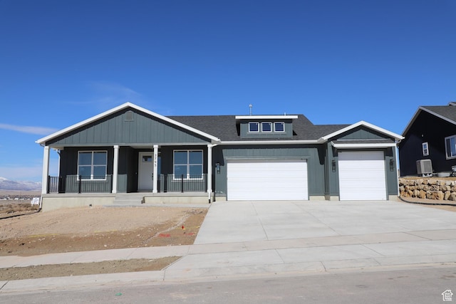 view of front facade with a porch, an attached garage, a shingled roof, concrete driveway, and board and batten siding