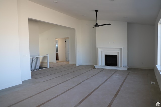 unfurnished living room featuring ceiling fan, baseboards, and a fireplace with raised hearth