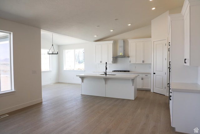 2794 E Liam Ln Unit 101, Eagle Mountain, UT 84005 - kitchen with wall chimney range hood, light countertops, white cabinetry, backsplash, and lofted ceiling