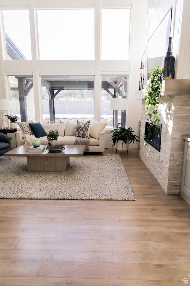 14102 S Sleepy Oaks Ln, Herriman, UT 84096 - living room featuring plenty of natural light, light wood-type flooring, a glass covered fireplace, and a towering ceiling