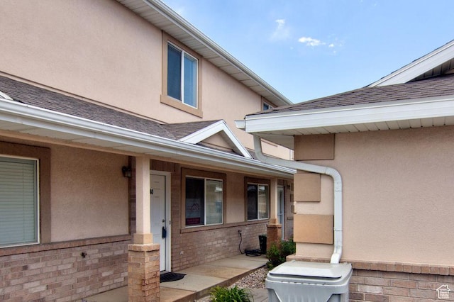 262 W 1975 N Unit 40, Ogden, UT 84414 - doorway to property featuring stucco siding, a shingled roof, a porch, and brick siding