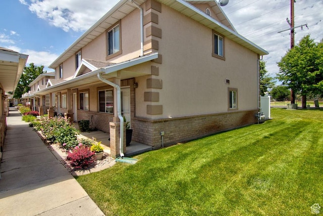 262 W 1975 N Unit 40, Ogden, UT 84414 - view of side of property with stucco siding, brick siding, a lawn, and covered porch