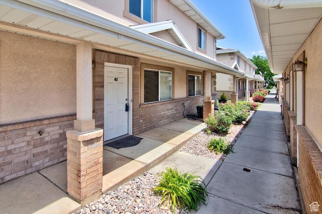 262 W 1975 N Unit 40, Ogden, UT 84414 - doorway to property featuring a porch, stucco siding, and brick siding