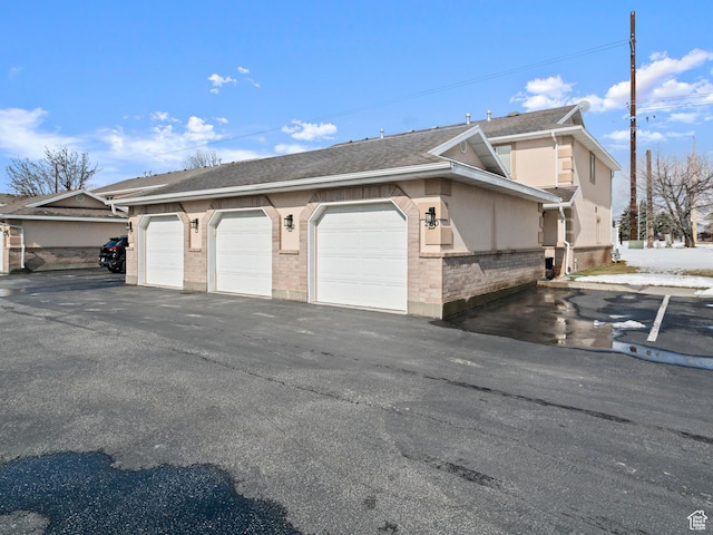 262 W 1975 N Unit 40, Ogden, UT 84414 - view of home's exterior with a shingled roof, brick siding, and community garages