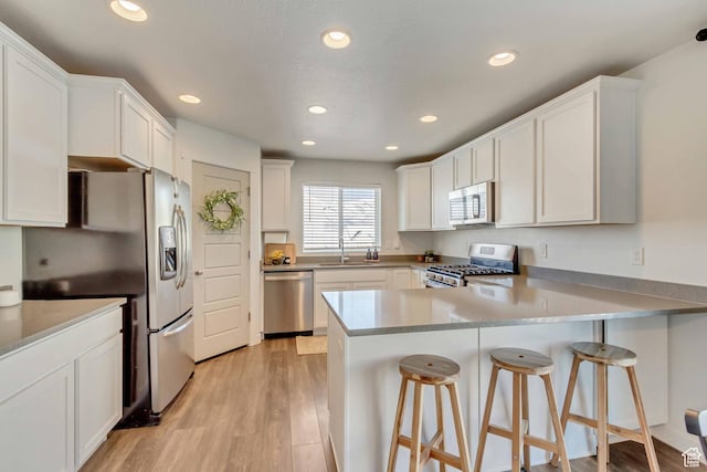 6393 N Pine Tree Way, Eagle Mountain, UT 84005 - kitchen featuring a sink, white cabinetry, a peninsula, light wood-style flooring, and stainless steel appliances