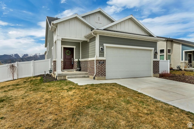 craftsman-style home featuring driveway, an attached garage, fence, board and batten siding, and a front lawn