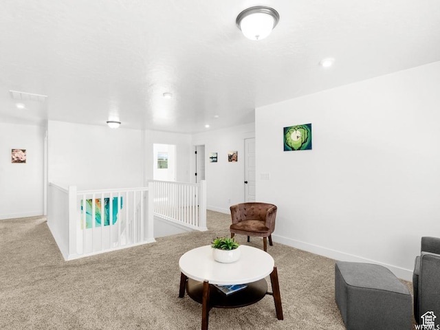 living area with light carpet, an upstairs landing, and baseboards
