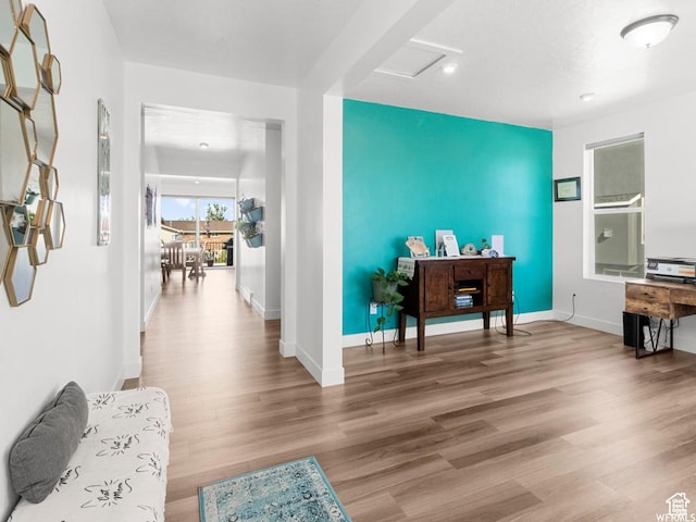 interior space featuring an accent wall, wood finished floors, attic access, and baseboards