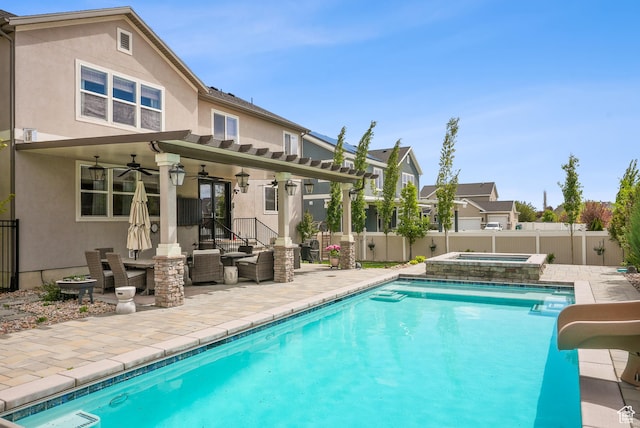 back of house with ceiling fan, stucco siding, an in-ground hot tub, and a fenced backyard