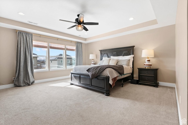 bedroom featuring a tray ceiling, light colored carpet, baseboards, and visible vents