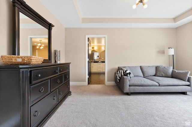 living room with a tray ceiling, baseboards, an inviting chandelier, and light colored carpet
