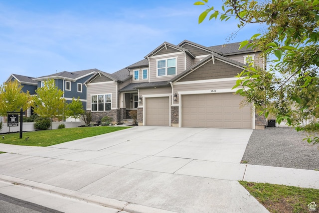 craftsman-style home with concrete driveway, a front yard, stone siding, and a garage