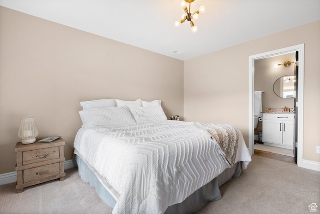 bedroom featuring ensuite bath, light carpet, baseboards, and a notable chandelier