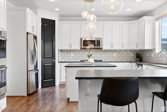 kitchen featuring appliances with stainless steel finishes, a sink, white cabinets, backsplash, and recessed lighting