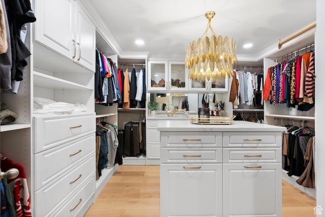 walk in closet with a chandelier and light wood-type flooring