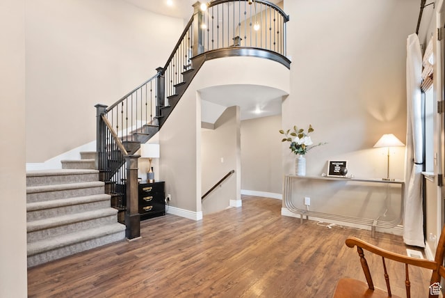 entryway with a high ceiling, wood finished floors, baseboards, and arched walkways
