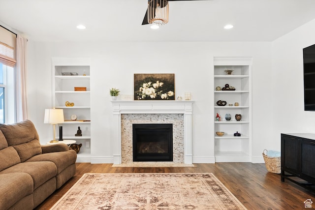living room with built in features, wood finished floors, a fireplace with flush hearth, and recessed lighting