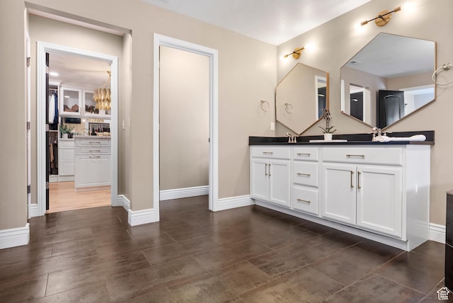 bathroom with double vanity, baseboards, and a sink