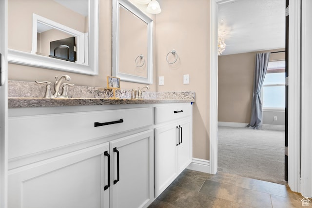 bathroom with a sink, double vanity, and baseboards