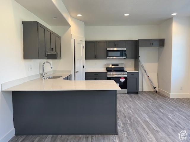 kitchen featuring gray cabinets, appliances with stainless steel finishes, light countertops, and a sink