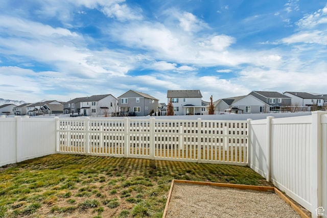 view of yard featuring a garden, a residential view, and a fenced backyard