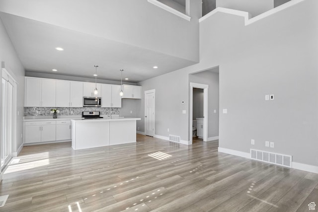 kitchen featuring visible vents, light wood-style floors, stainless steel appliances, and white cabinetry