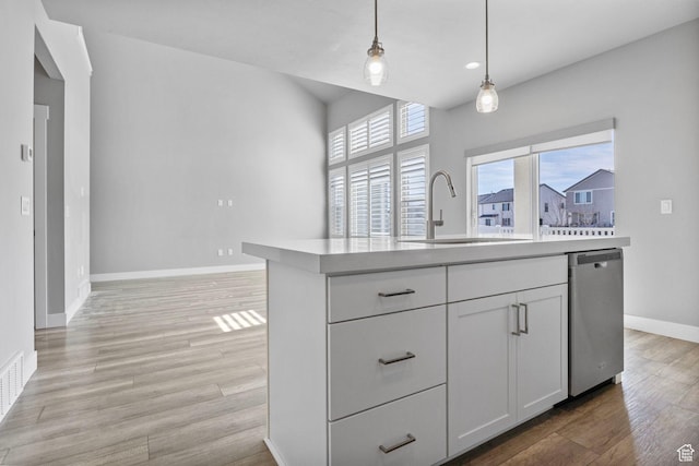 kitchen with white cabinetry, light wood-style flooring, a sink, dishwasher, and decorative light fixtures