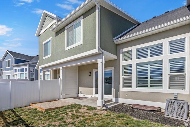 rear view of house with a patio area, stucco siding, central AC, and fence