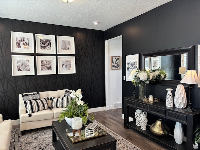 living room featuring a textured ceiling, wood finished floors, visible vents, and baseboards