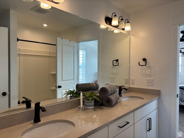 ensuite bathroom featuring double vanity, a sink, visible vents, and ensuite bathroom