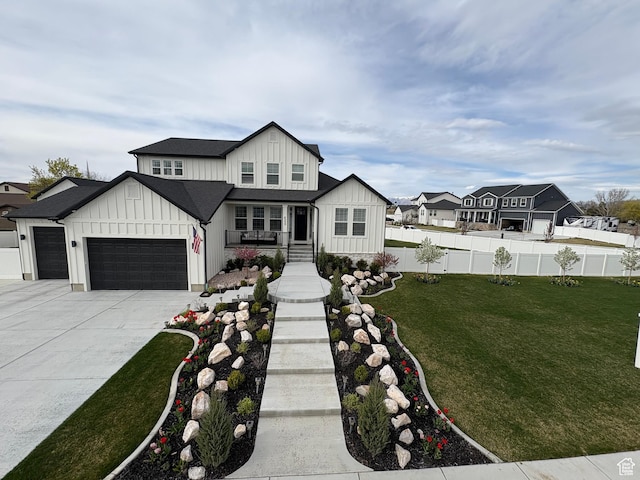modern farmhouse with a garage, concrete driveway, board and batten siding, fence, and a front yard