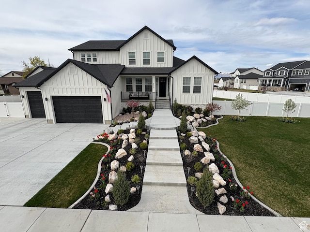 modern farmhouse style home featuring a front lawn, fence, board and batten siding, and a garage