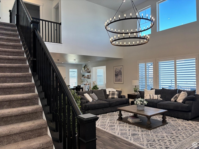living area with stairs, dark wood-style floors, a high ceiling, and a chandelier