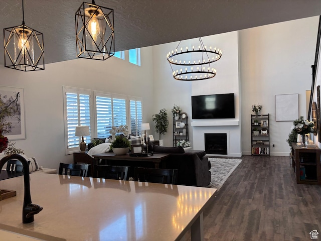 dining room featuring a high ceiling, an inviting chandelier, dark wood-type flooring, baseboards, and a fireplace