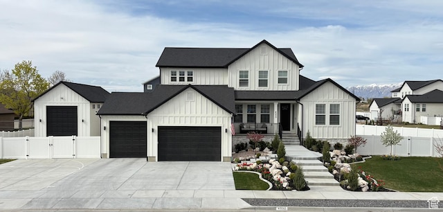 modern inspired farmhouse with a gate, concrete driveway, board and batten siding, fence, and a garage