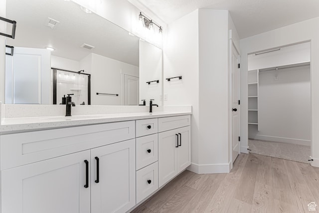 706 W 4500 S Unit 307, Mapleton, UT 84664 - bathroom with a shower stall, double vanity, wood finished floors, a spacious closet, and baseboards