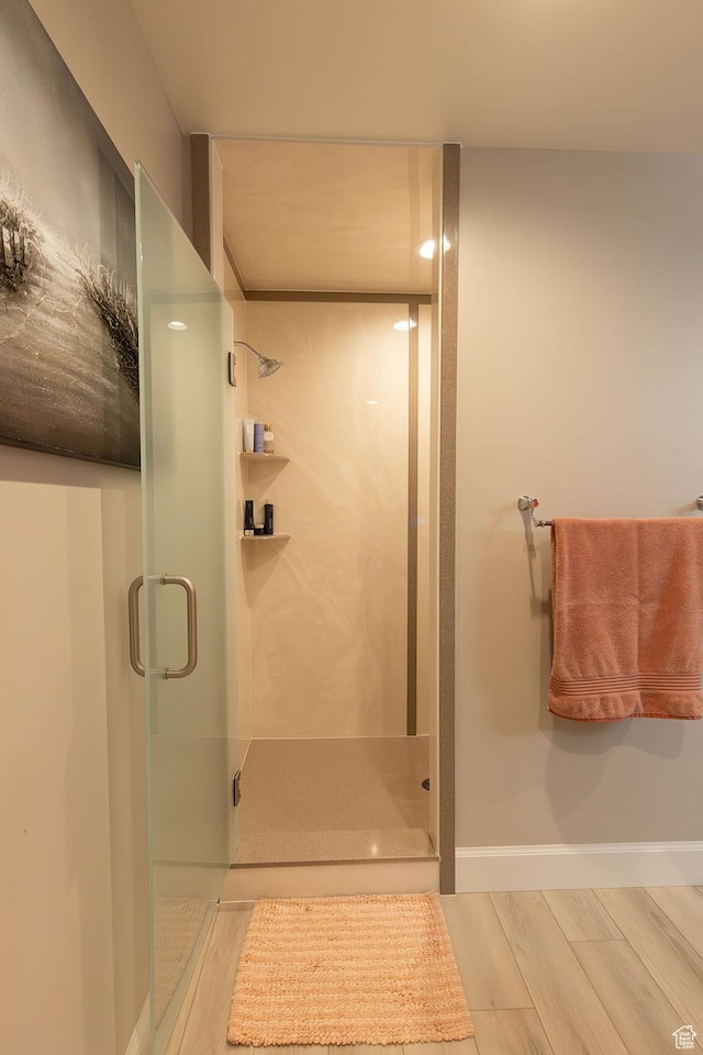 full bathroom featuring a shower stall, baseboards, and wood finished floors