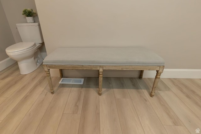 room details with toilet, baseboards, visible vents, and wood finished floors