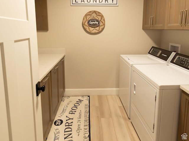 washroom featuring light wood-type flooring, cabinet space, washer and clothes dryer, and baseboards