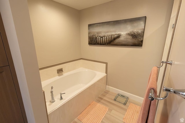 full bathroom featuring a garden tub, baseboards, and wood finished floors