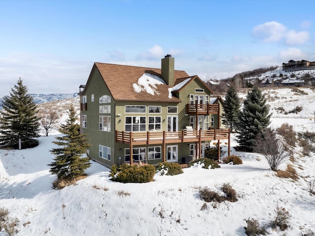1173 S Innsbruck Dr, Huntsville, UT 84317 - snow covered back of property featuring a wooden deck, stucco siding, a balcony, and a chimney