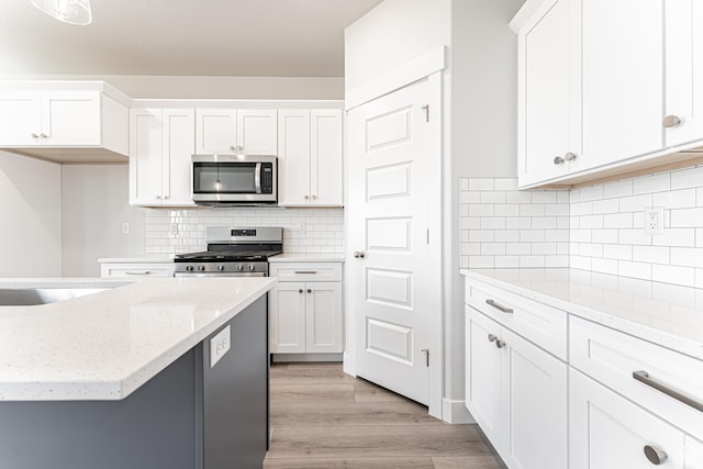 702 W 4500 S Unit 308, Mapleton, UT 84664 - kitchen with stainless steel appliances, white cabinetry, light wood-type flooring, and decorative backsplash