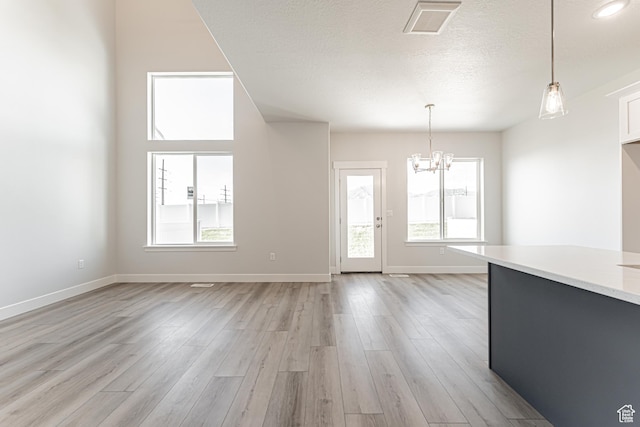 702 W 4500 S Unit 308, Mapleton, UT 84664 - unfurnished living room with a chandelier, light wood-type flooring, baseboards, and a textured ceiling