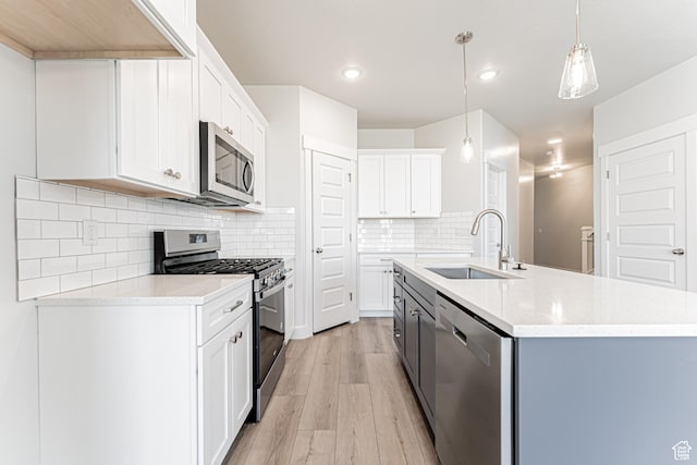 702 W 4500 S Unit 308, Mapleton, UT 84664 - kitchen featuring stainless steel appliances, light wood-style flooring, a sink, a kitchen island with sink, and hanging light fixtures