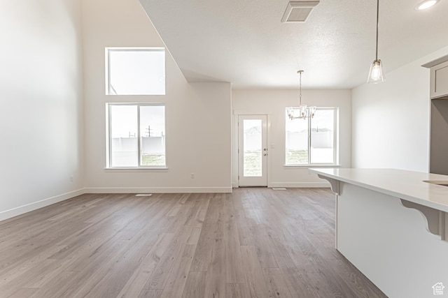 698 W 4500 S Unit 309, Mapleton, UT 84664 - unfurnished living room with a chandelier, light wood-style flooring, baseboards, and a textured ceiling