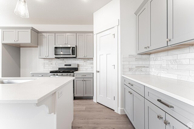 698 W 4500 S Unit 309, Mapleton, UT 84664 - kitchen with stainless steel appliances, gray cabinetry, light wood-type flooring, backsplash, and light countertops