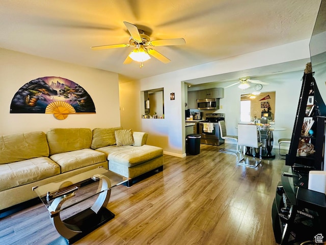 living area with baseboards, a ceiling fan, and wood finished floors