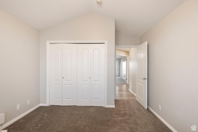 unfurnished bedroom featuring baseboards, vaulted ceiling, a closet, and carpet