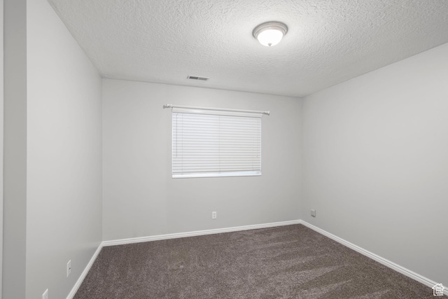 unfurnished room with dark carpet, baseboards, visible vents, and a textured ceiling